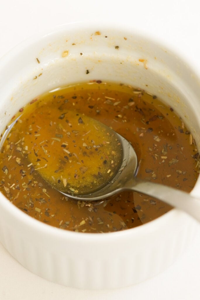 olive oil with seasoning in a small bowl with a silver spoon.