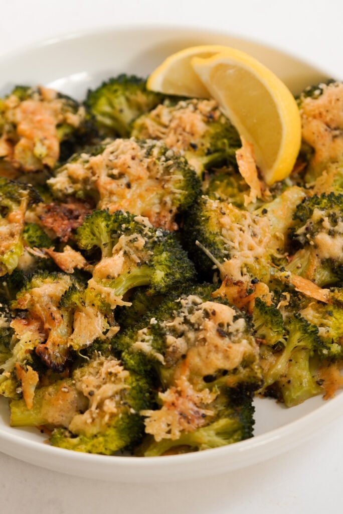 bowl of smashed broccoli with parmesan cheese and lemon.