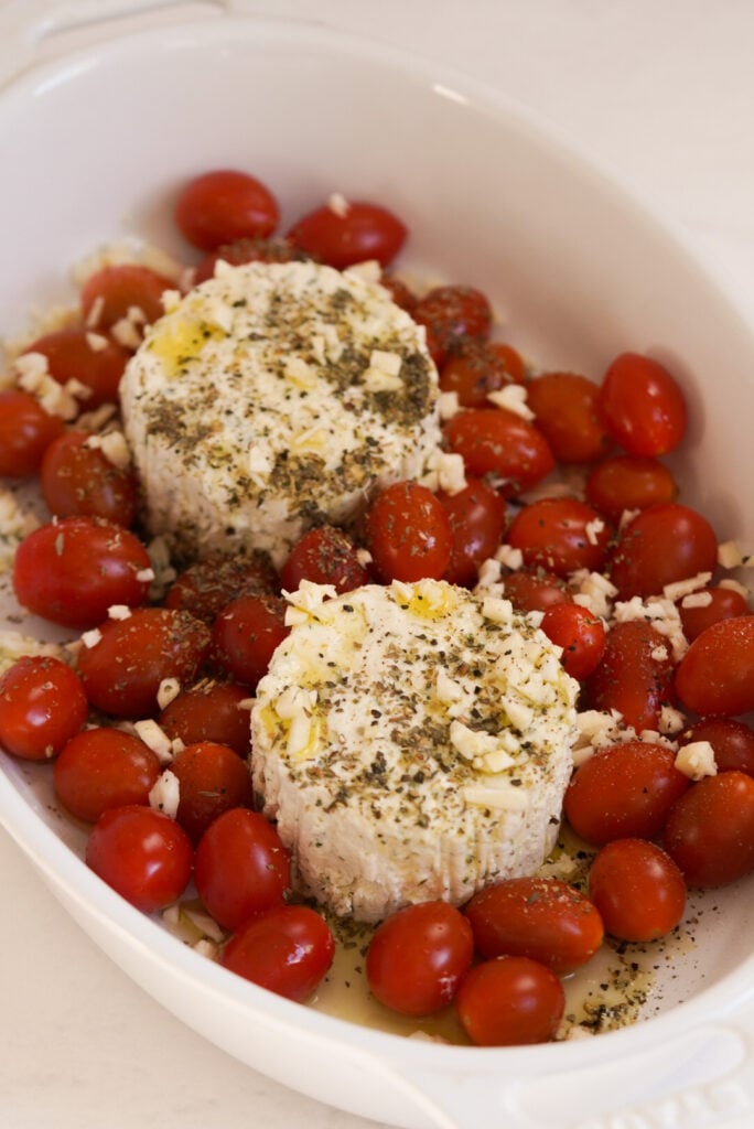 process shot showing the boursin cheese rounds and tomatoes in a baking dish before baking.