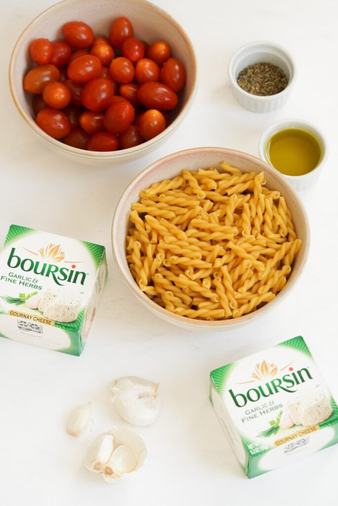flat lay shot of the ingredients needed to make boursin pasta measured out into bowls on a white table.