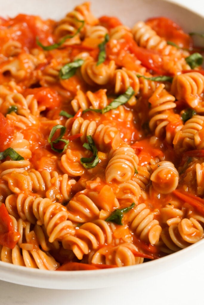 bowl of cherry tomato sauce pasta on a white table.