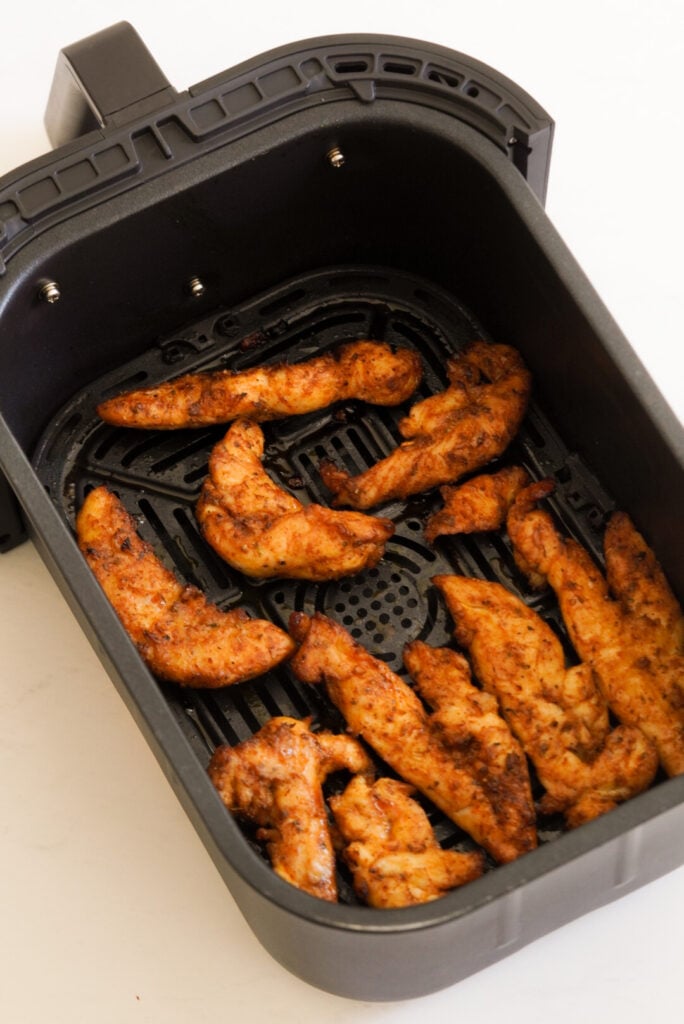 air fried chicken tenderloins in the air fryer basket after cooking.