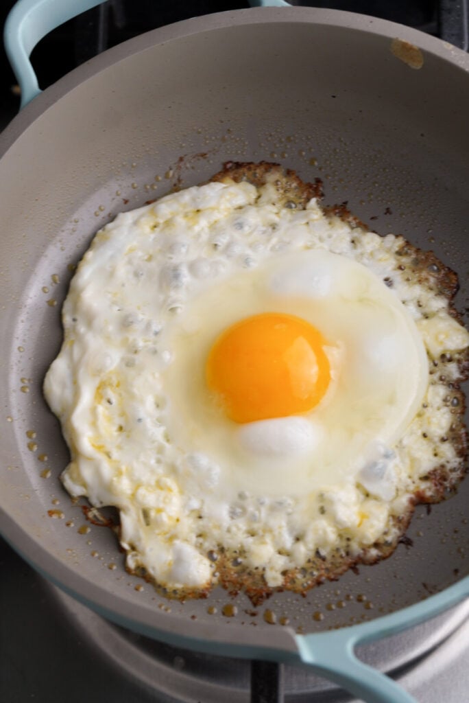 egg frying in feta cheese in a small pan