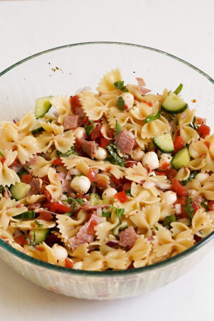 bow tie pasta salad in a mixing bowl after tossing with the italian dressing.