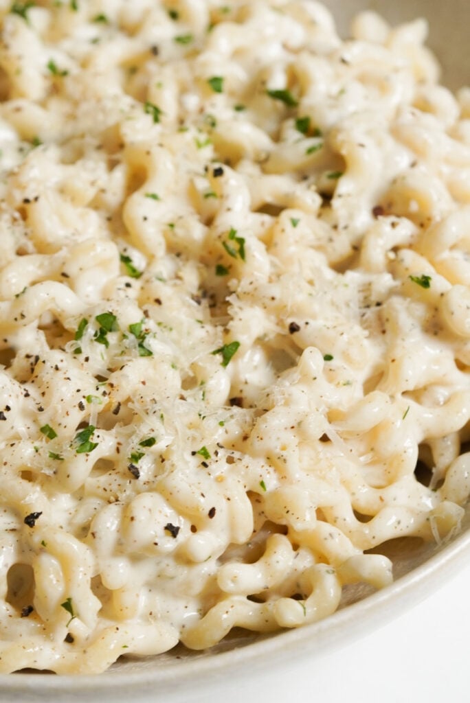 pasta in cottage cheese alfredo sauce in a white serving bowl.