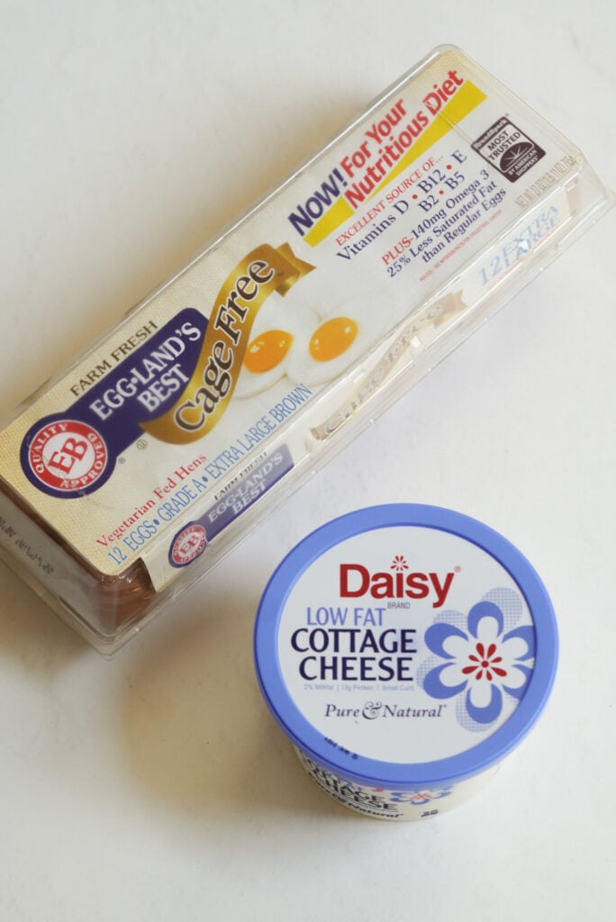 container of Daisy cottage cheese and a tray of egglands best cage free eggs on a white table. 