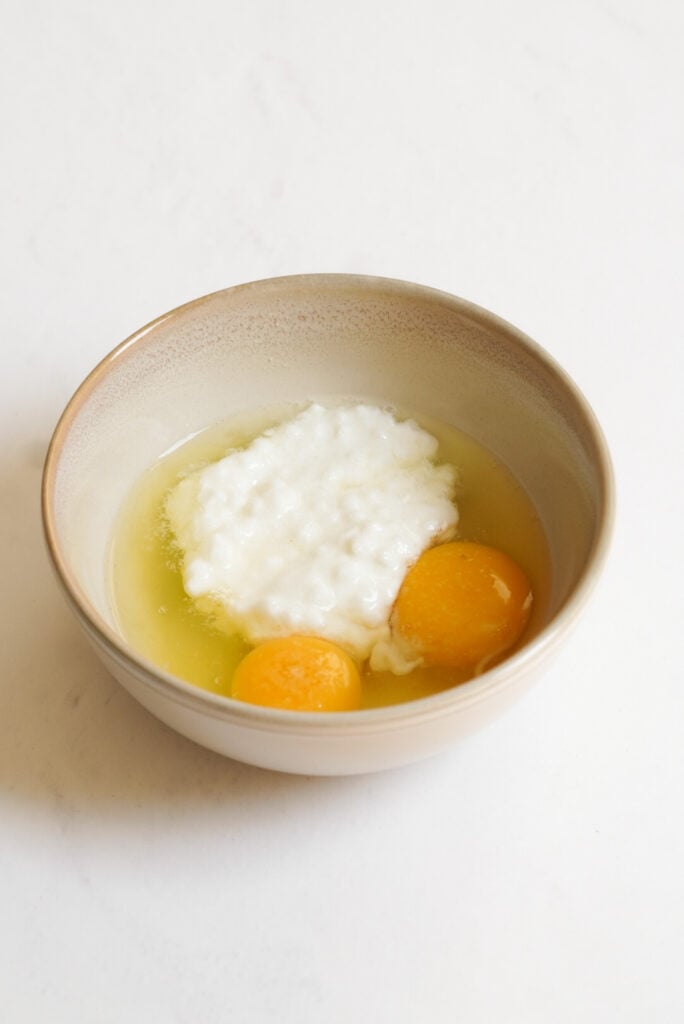 two whole eggs and a scoop of cottage cheese in a small bowl. 