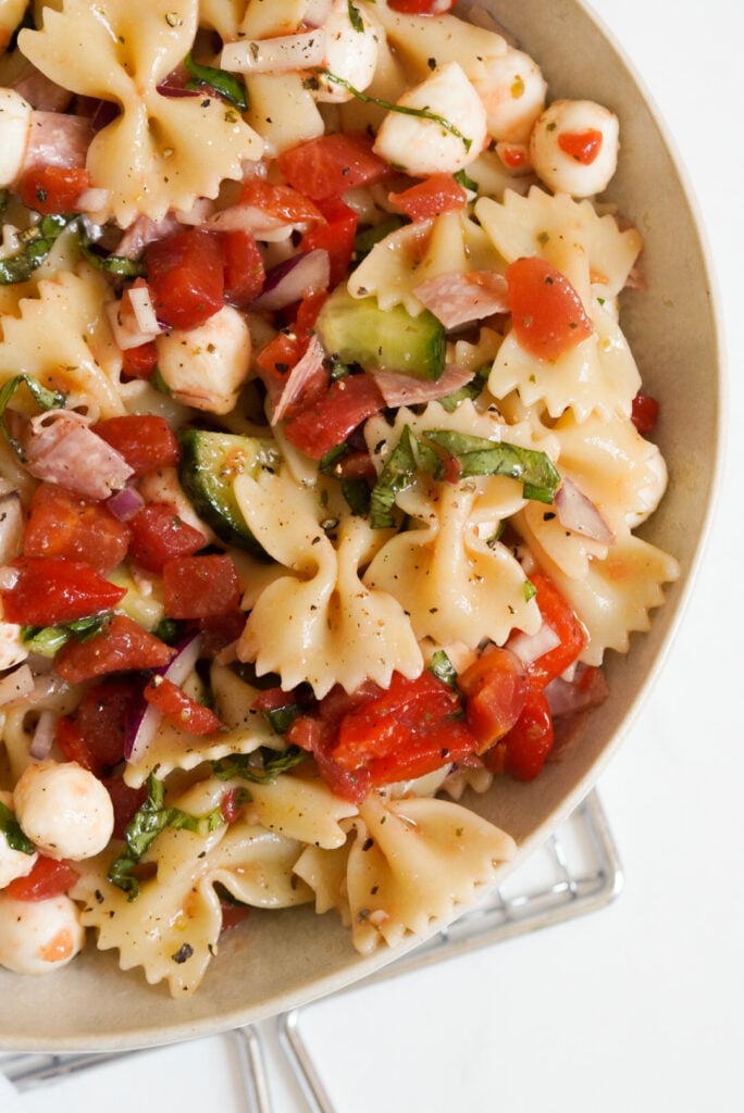 flat lay shot of 1/2 a serving bowl of italian bow tie pasta salad.