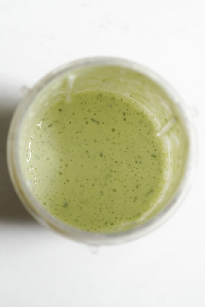 overhead shot of greek yogurt ranch dressing in the base of a smoothie blender after blending.