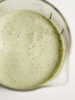 overhead shot of greek yogurt ranch salad dressing in a measuring glass with a pour spout.