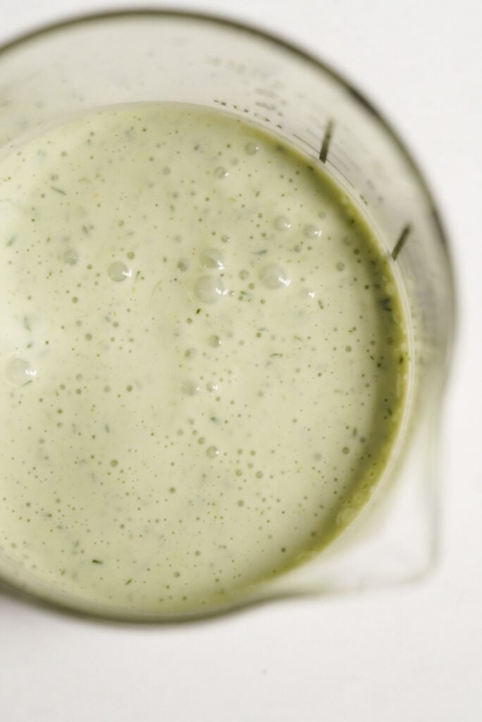 overhead shot of greek yogurt ranch salad dressing in a measuring glass with a pour spout.