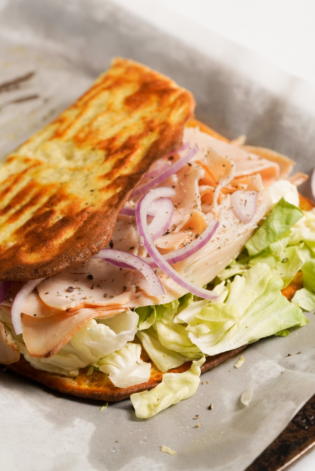 egg and cottage cheese flatbread folded over the turkey sandwich ingredients revealing the golden brown underside.