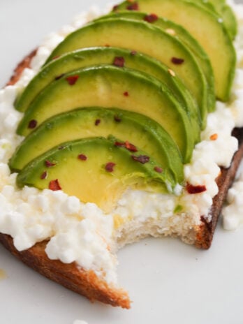 45 degree angle view of avocado and cottage cheese toast with a bite taken out.