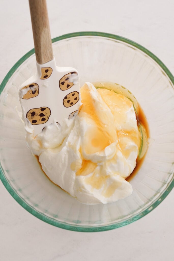 greek yogurt, vanilla, and honey added to a clear mixing bowl.