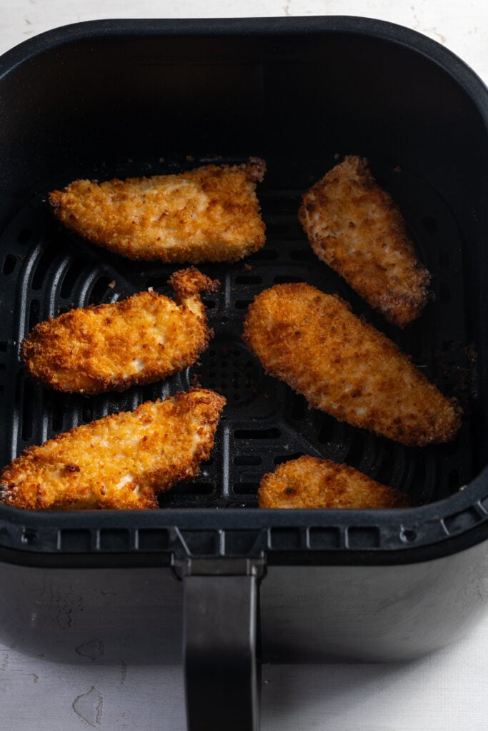 6 homemade spicy chicken tenders in the base of an air fryer.