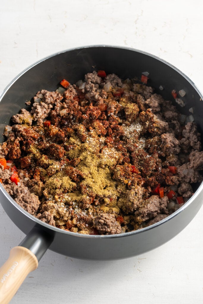 seasonings sprinkled atop the ground beef and veggie mixture in the skillet.