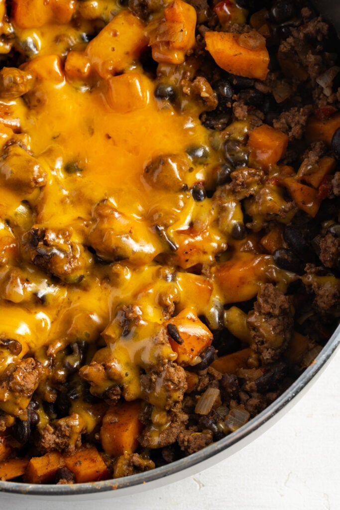 closeup shot of the melted cheese topping on the Southwestern ground beef sweet potato skillet in the pan.