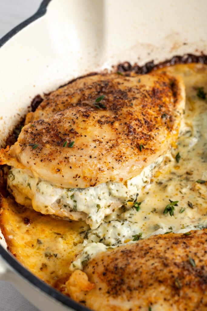 chicken breasts stuffed with cream cheese cooking in a pan.