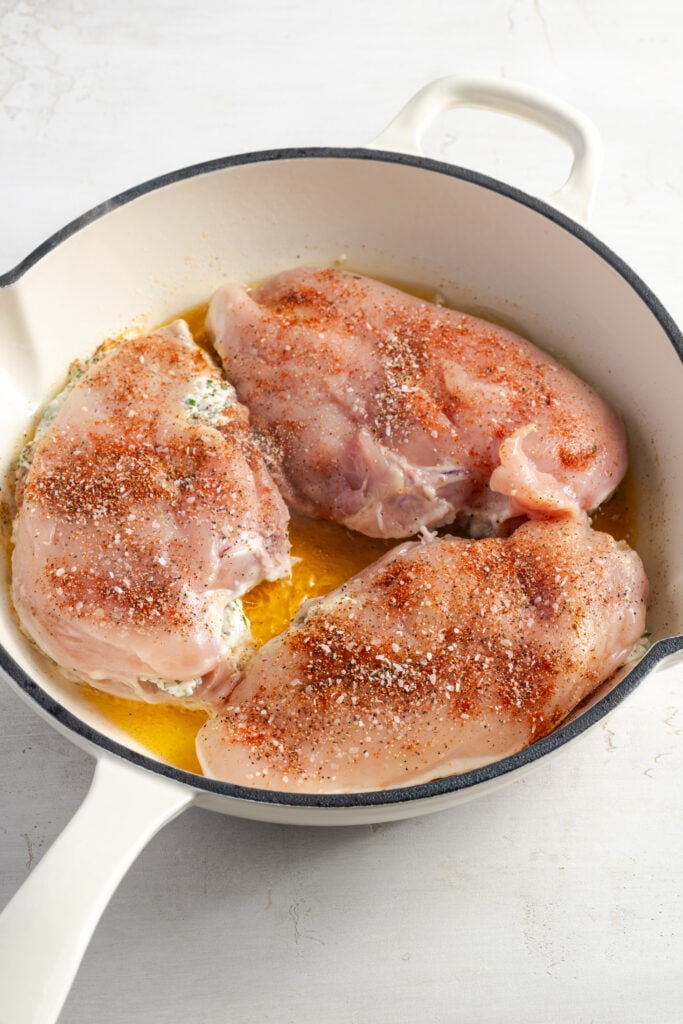 raw cream cheese stuffed chicken breasts in a pan with hot oil.