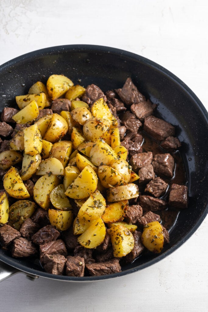 cooked potatoes added back to the pan with the garlic butter steak bites.