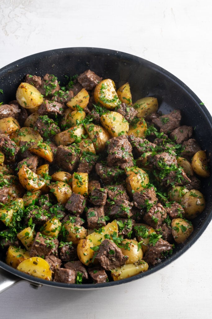 garlic butter steak bites and potatoes in the skillet after removing from heat and sprinkling with fresh parsley that has yet to be mixed in.