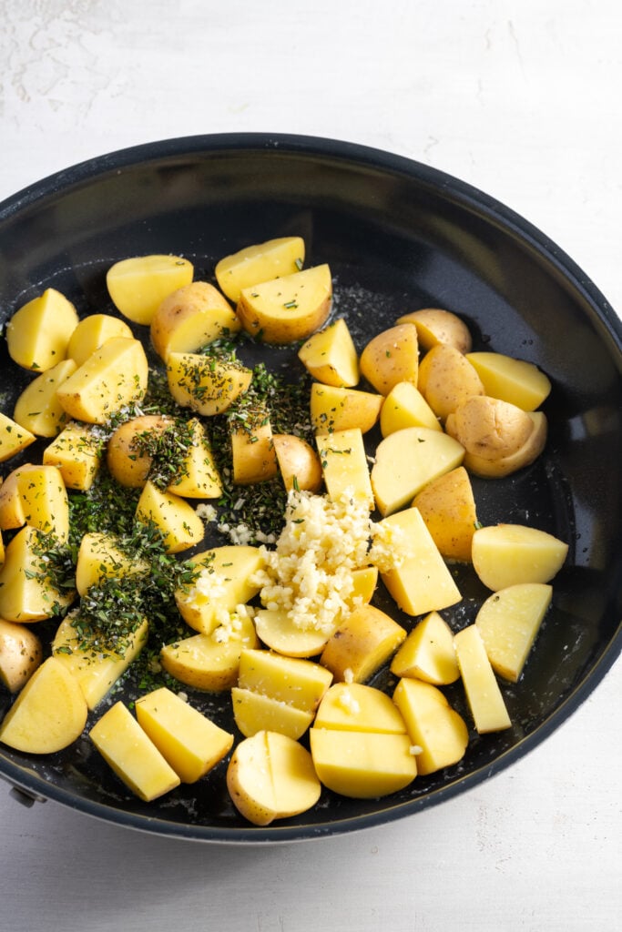 raw potato chunks and seasonings added to a hot skillet to sear.