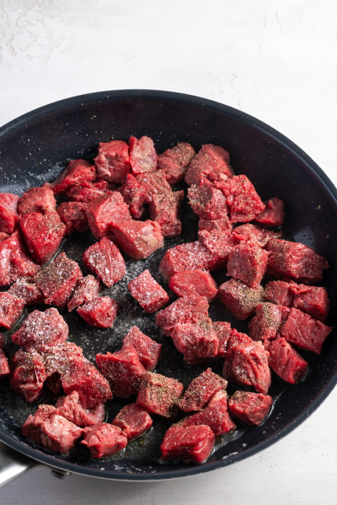 seasoned steak bites being seared in a hot pan.