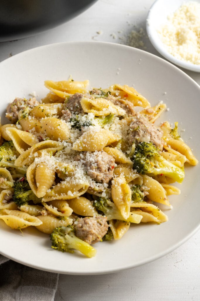 easy ground turkey pasta plated on a round white pasta plate with a smaller bowl of parmesan cheese shreds in the top right of the frame.