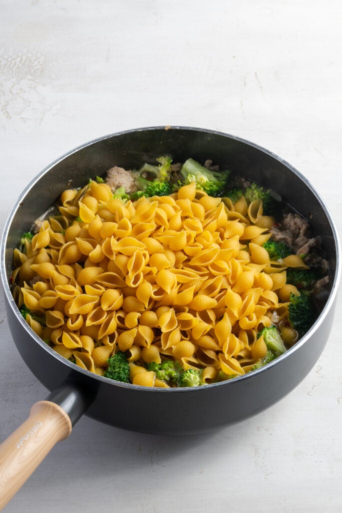 pasta shells added to the skillet with the broth, broccoli, and ground turkey.