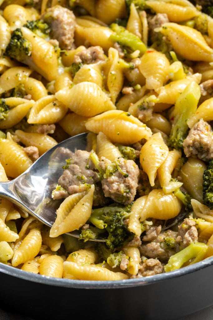 serving spoon taking a spoonful of ground turkey pasta dinner out of the skillet to plate.