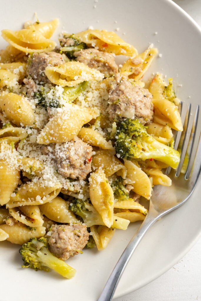 closeup shot of broccoli and ground turkey pasta in a bowl after garnishing with parmesan.
