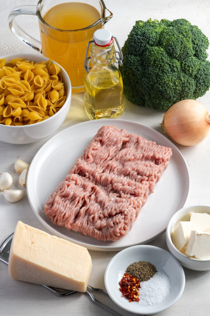 ingredients needed to make broccoli ground turkey pasta measured out on a white table.