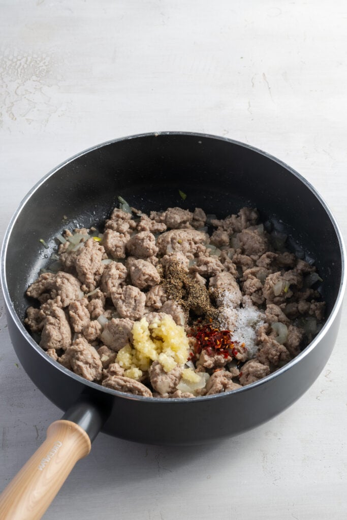 cooked ground turkey in a skillet with garlic and spices added.