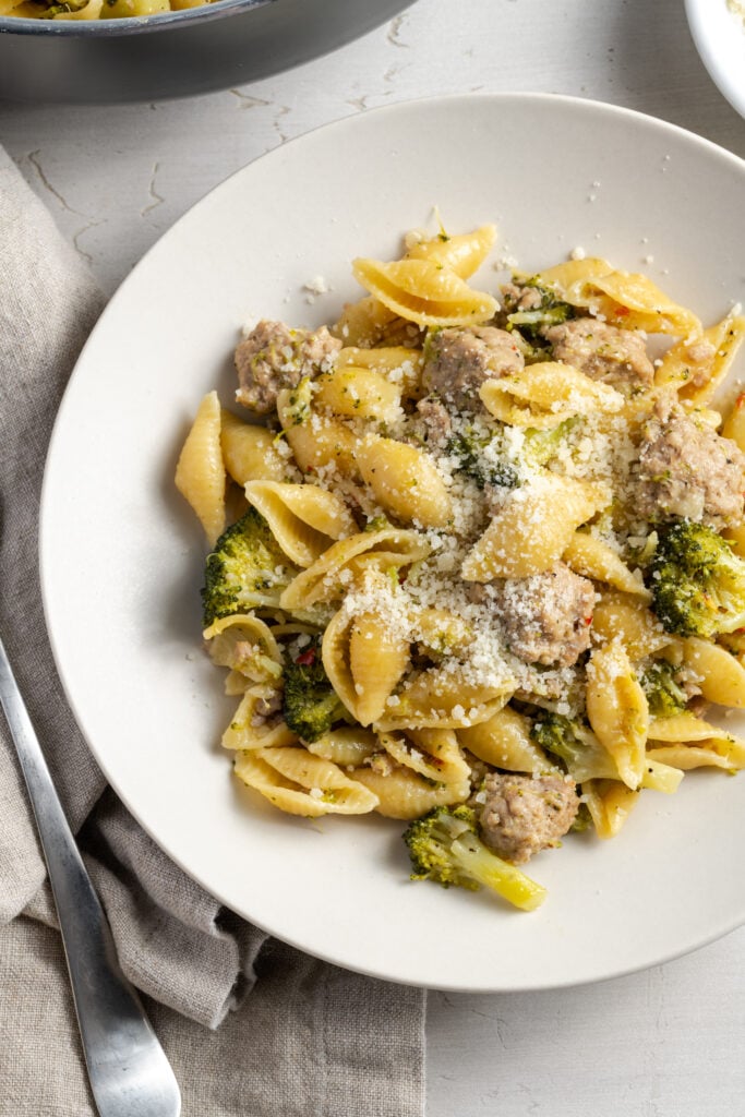 dinner plate with light ground turkey pasta topped with freshly grated parmesan with a light grey linen napkin and a silver utensil to the left.