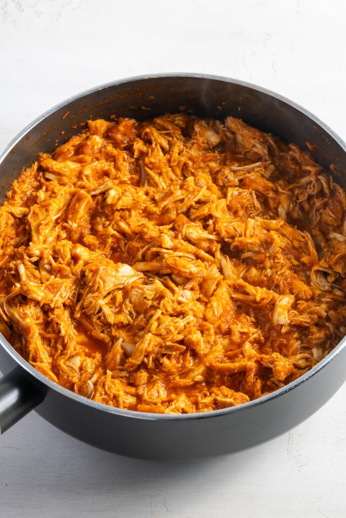 shredded cooked chicken tossed in the spicy tomato tinga sauce in a large skillet.