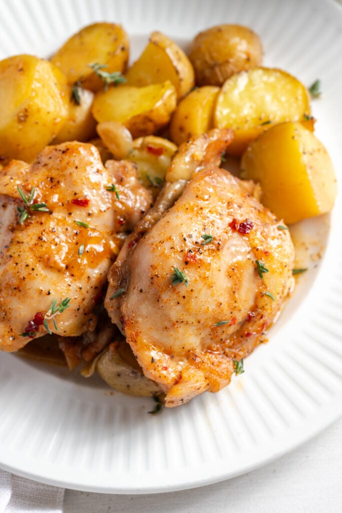 closeup shot of juicy looking one dish chicken thighs and potatoes.