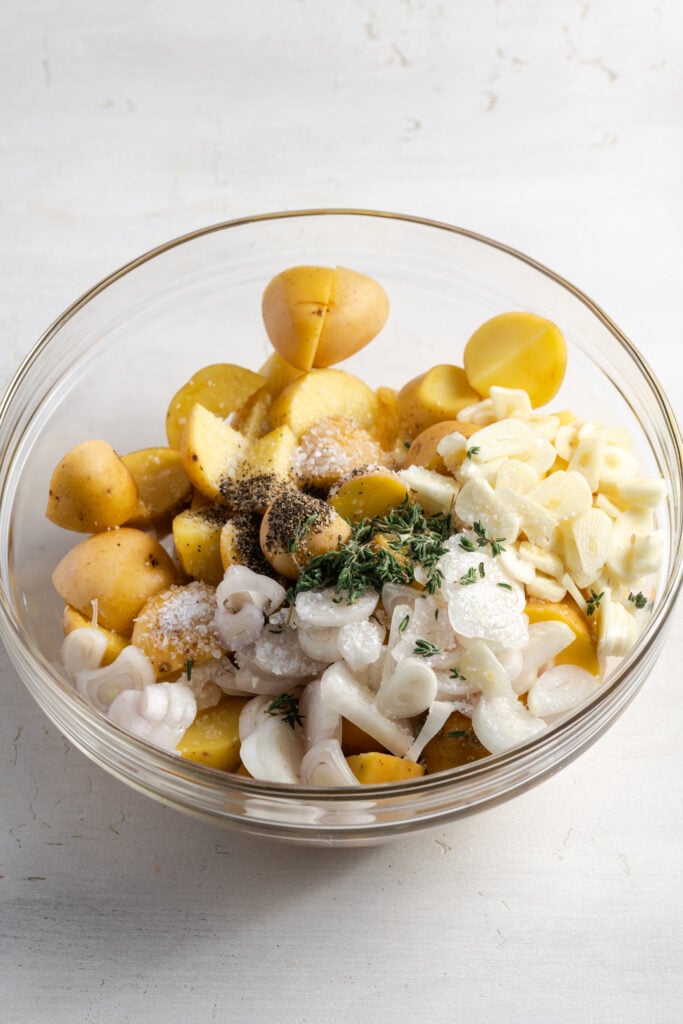 potatoes, garlic, onion, and seasonings in a glass mixing bowl before tossing.