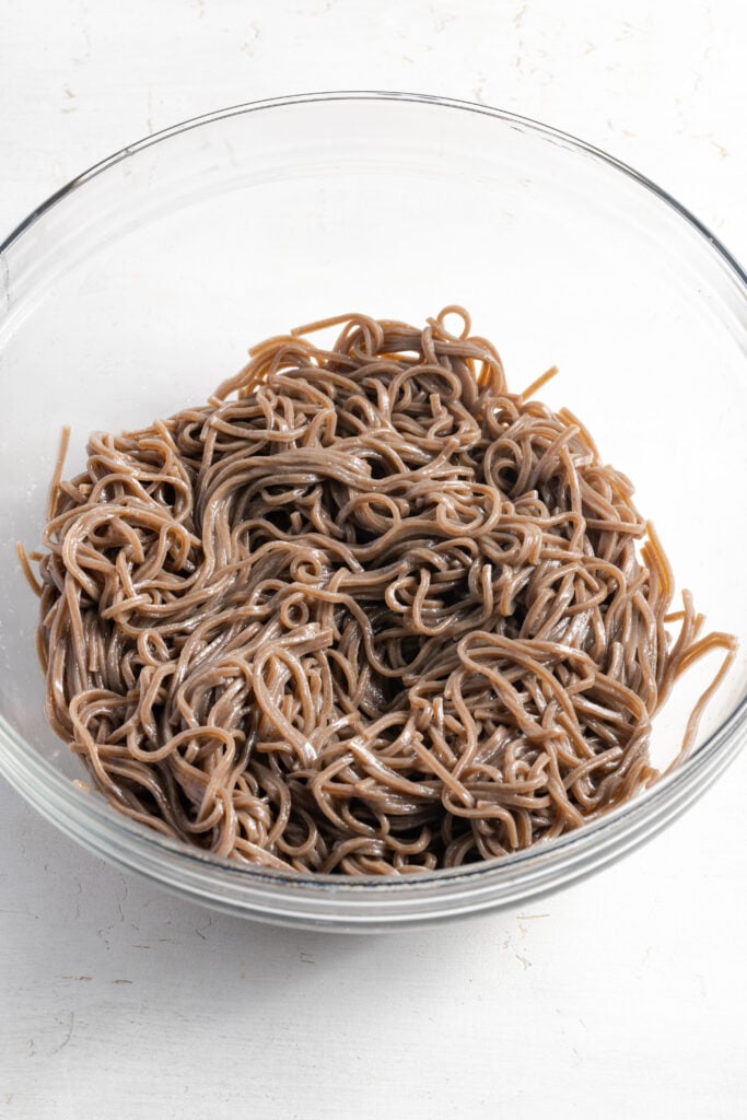 cooked soba noodles in a mixing bowl after rinsing and tossing with oil.