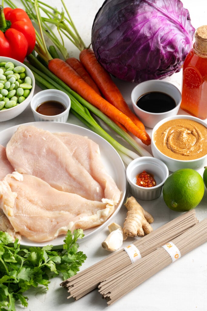 ingredients needed for making Thai peanut noodle salad with chicken measured out on a white table.
