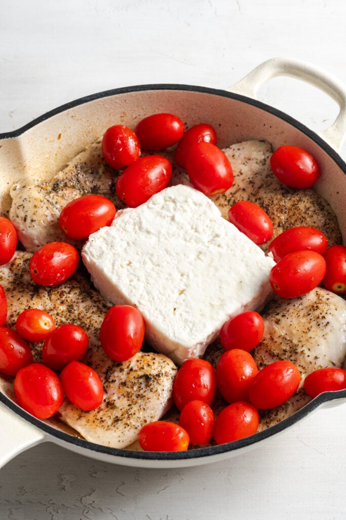 feta and raw grape tomatoes added to the skillet on top of the chicken breasts.