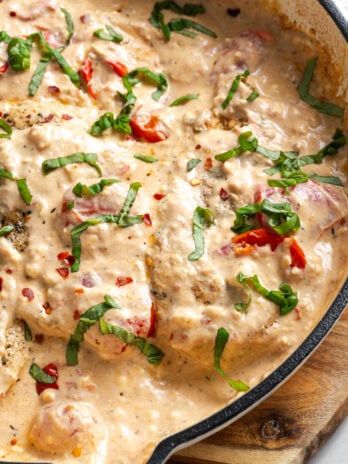 closeup shot of feta tomato chicken bake in the skillet after garnishing with basil.