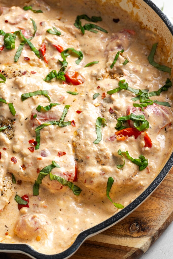 closeup shot of feta tomato chicken bake in the skillet after garnishing with basil.