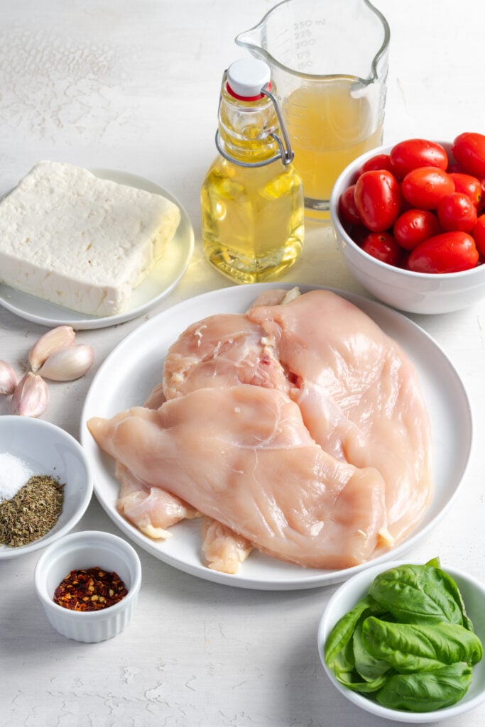 ingredients for feta tomato chicken bake recipe measured out on a white table.