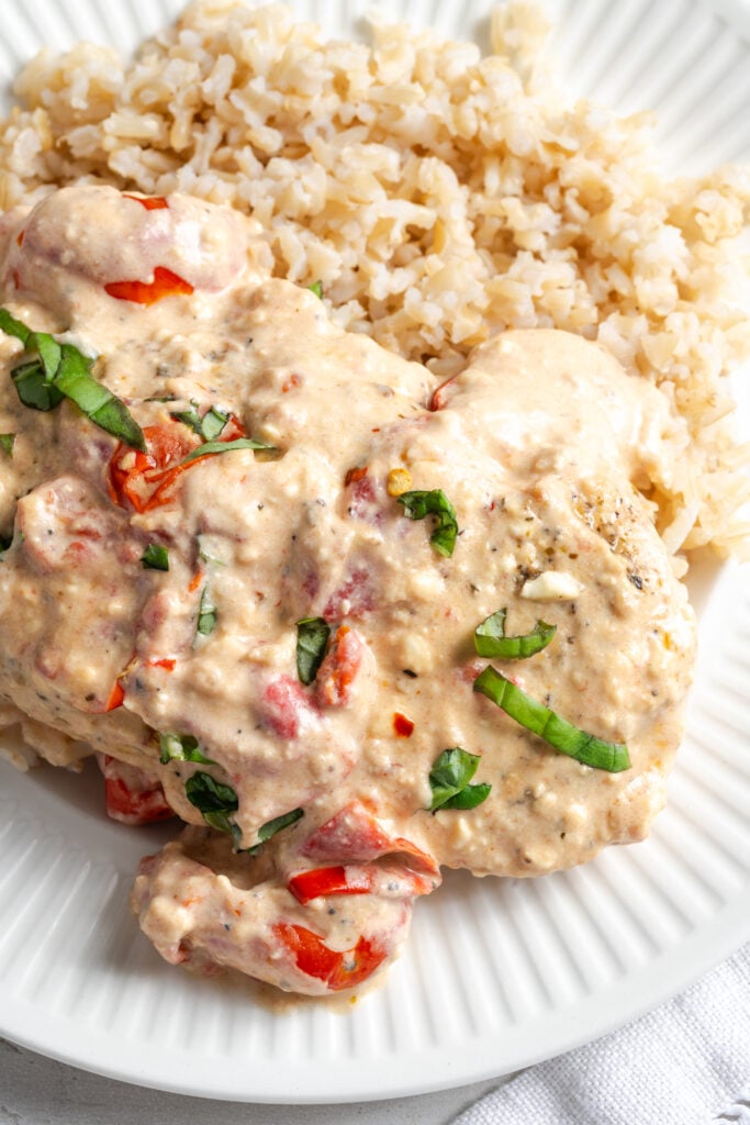 closeup shot of feta tomato chicken breast topped with creamy feta sauce and basil.