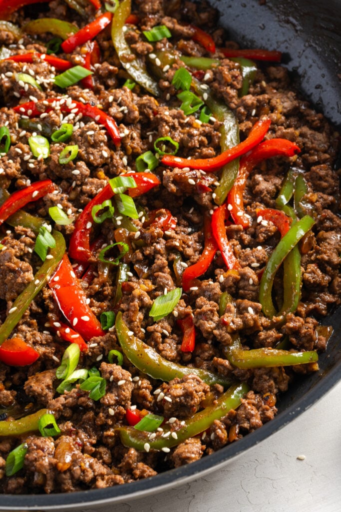 right half of a skillet filled with ground beef and peppers in a spicy soy sauce.