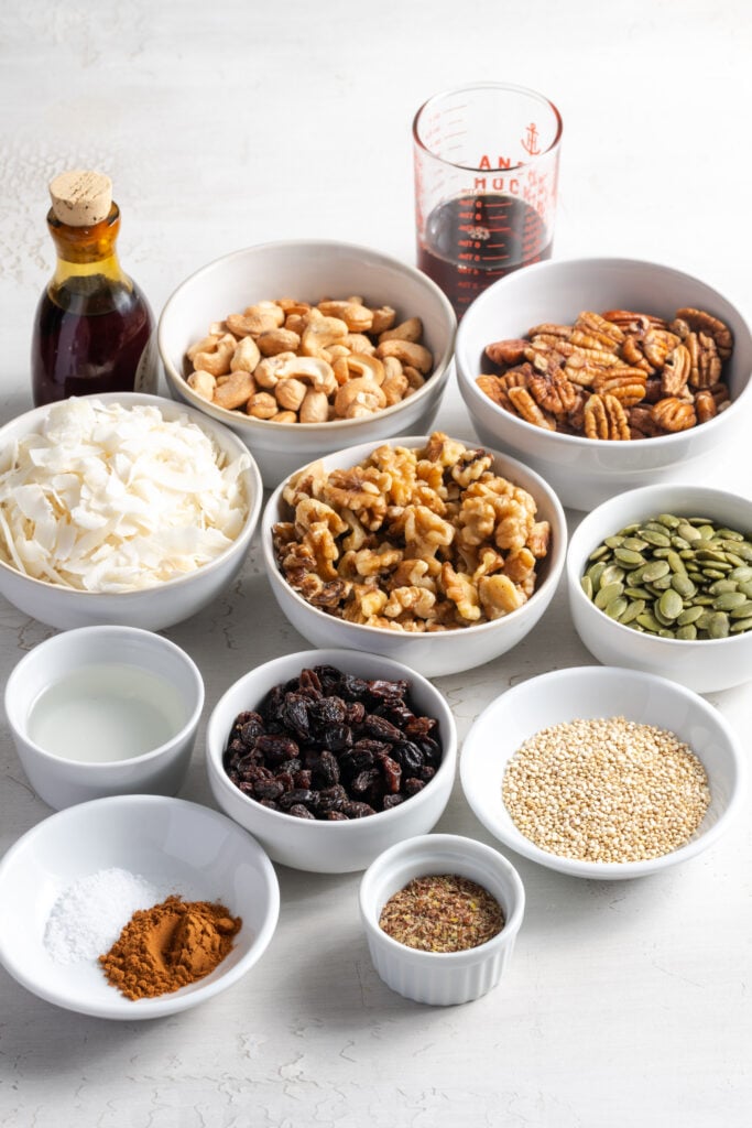 ingredients needed to make grain free granola recipe measured out in bowls on a white table.