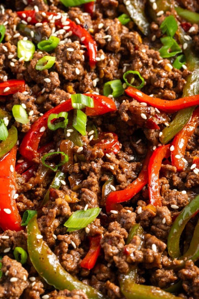 closeup shot of ground beef and peppers in an Asian inspired sauce topped with green onions and sesame seeds.
