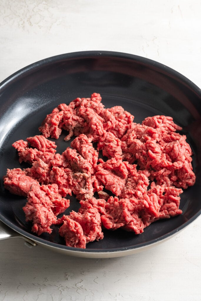 raw ground beef cooking in a nonstick skillet.
