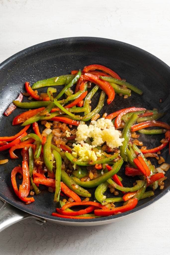 bell pepper strips in a pan with garlic and ginger.