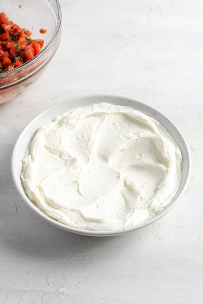 whipped ricotta spooned into a serving bowl and spread to the edges with the back of a spoon.